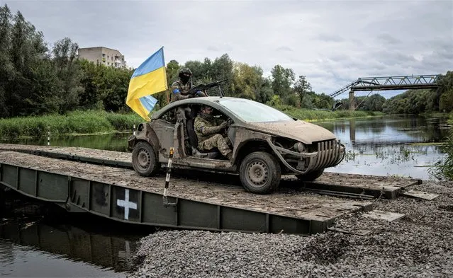 Ukrainian paratroopers drive on the vehicle with Ukrainian flag on the pantone bridge across Siverskiy-Donets river in the recently retaken area of Izium, Ukraine, Wednesday, September 14, 2022. (Photo by Evgeniy Maloletka/AP Photo)