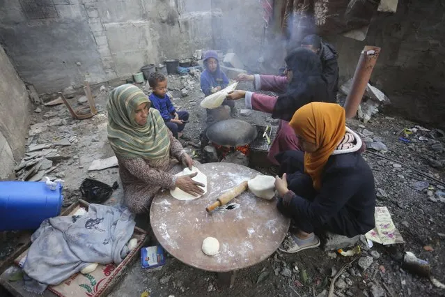 Palestinians bake bread by their destroyed homes in Kuza' a Gaza Strip during the temporary ceasefire between Hamas and Israel on Wednesday, November 29, 2023. (Photo by Hatem Ali/AP Photo)