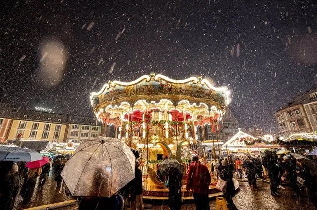 Snow falls as the traditional Christmas market with the merry-go-round was opened in Frankfurt, Germany, Monday, November 27, 2023. (Photo by Michael Probst/AP Photo)