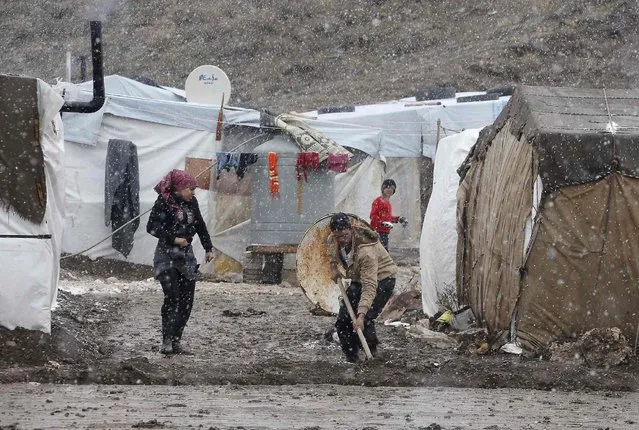 A Syrian refugee works outside his tent during a winter storm in Zahle town, in the Bekaa Valley December 11, 2013. The worst of winter is yet to come for 2.2 million refugees living outside Syria and millions more displaced inside the country. A(Photo by Mohamed Azakir/Reuters)