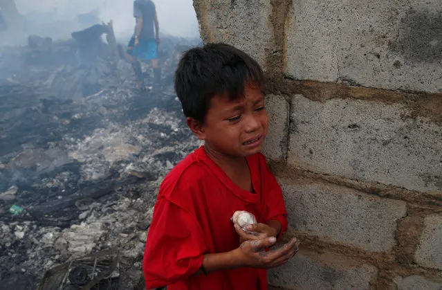 A boy cries after he injured his hand while recovering recyclable materials after a fire at a squatter colony in Navotas, Metro Manila in the Philippines January 10, 2017. (Photo by Erik De Castro/Reuters)