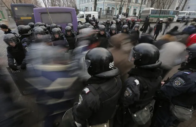 Pro-European Union activists pass through a police line as they march against the government in Kiev, Ukraine, Tuesday, December 17, 2013. Weeks of angry pro-European Union protests as well as Western pressure have forced Yanukoyvch to make some concessions to the opposition. Last week Yanukovych called for an amnesty for some of the activists detained. (Photo by Dmitry Lovetsky/AP Photo)