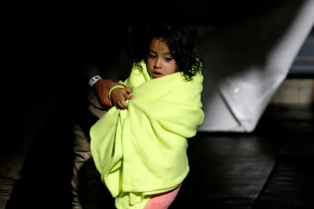 A young migrant girl is wrapped in a blanket on the German NGO migrant rescue ship Sea-Watch 3 after being rescued from a wooden boat in the Maltese search and rescue zone in international waters off the coast of Libya, in the western Mediterranean Sea, July 29, 2021. (Photo by Darrin Zammit Lupi/Reuters)