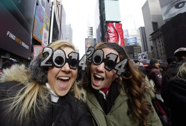 Veronica Boshen and Brittany Wells, of Allentown, Pa., pose for a photo with their 2014 glasses while waiting for the celebration to begin in Times Square on New Year's Eve, Tuesday, December 31, 2013, in New York. (Photo by Kathy Willens/AP Photo)