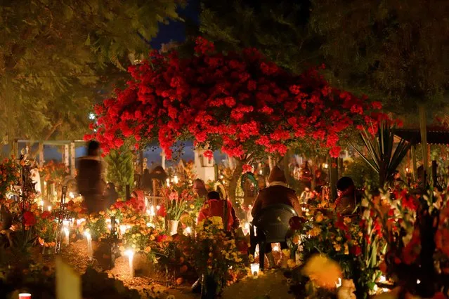 Indigenous people stand by the graves of their relatives during the annual Day of the Dead celebration, at a cemetery in Santa Maria Atzompa, Oaxaca, Mexico on November 1, 2022. (Photo by Jorge Luis Plata/Reuters)