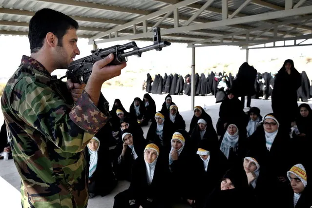 In this Thursday, August 22, 2013 photo, a trainer of the Basij paramilitary militia shows female Basij members how to use an AK-47 rifle during a training session in Tehran, Iran. (Photo by Ebrahim Noroozi/AP Photo)