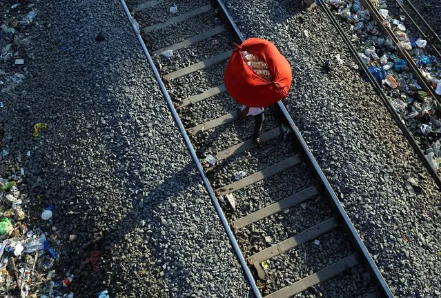A man carries “paani puri”, a traditional Indian snack, on his head on a railway track in Mumbai, India January 23, 2017. (Photo by Danish Siddiqui/Reuters)