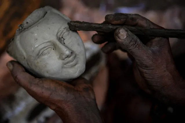 An artist works on an idol of Indian Hindu goddess Durga at a workshop ahead of the Durga puja festival in Hyderabad on September 28, 2021. (Photo by Noah Seelam/AFP Photo)