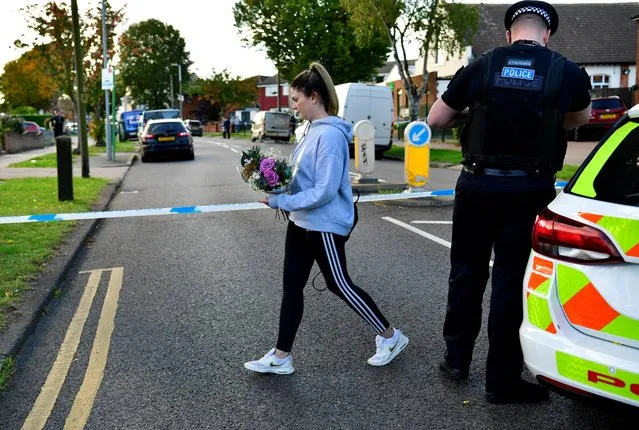 A woman brings flowers to the scene where MP David Amess was stabbed during constituency surgery, in Leigh-on-Sea, Britain on October 15, 2021. British Conservative lawmaker David Amess has died after being stabbed Friday during a meeting with constituents at a church in eastern England. A 25-year-old man has been arrested. (Photo by Tony O'Brien/Reuters)