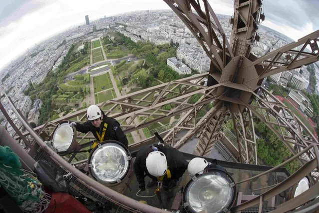 Technician David Kalic (L) and colleagues clean and change some of the sodium golden light bulbs on the Eiffel tower in Paris, France, May 5, 2015. (Photo by Philippe Wojazer/Reuters)