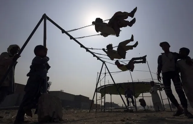 Children ride swings in a playground in Karachi, Pakistan, Friday, November 19, 2021. (Photo by Fareed Khan/AP Photo)