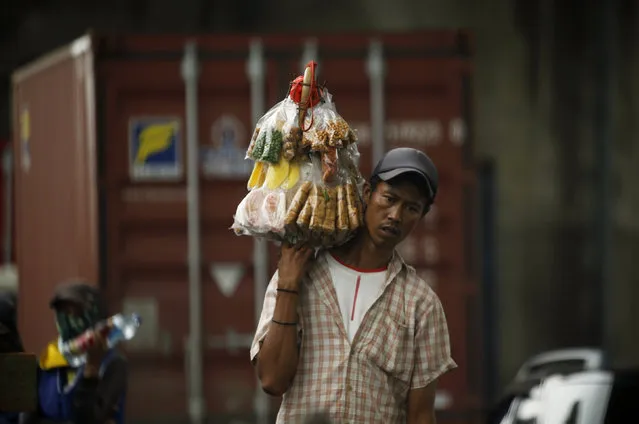A street vendor carries snacks for sale at the street in Jakarta, Indonesia, March 30, 2016. (Photo by Reuters/Beawiharta)