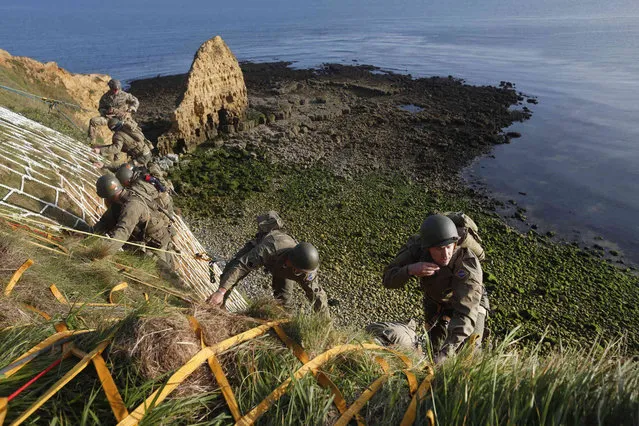 Soldiers from the U.S. 75th Ranger Regiment, in period dress, climb the cliff of Pointe-du-Hoc in Cricqueville-en-Bessin, Normandy, France, Wednesday, June 5, 2019. During the American assault of Omaha and Utah beaches on June 6, 1944, U.S. Army Rangers scaled the 100-foot cliffs to seize German artillery pieces that could have fired on the American landing troops. (Photo by Thibault Camus/AP Photo)