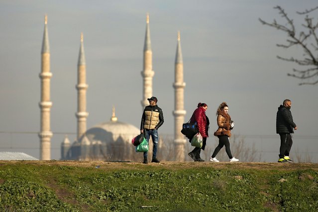 Bulgarian tourists walk to their cars with shopping bags in Edirne, near Bulgaria border, in Turkey, Friday, December 24, 2021. Bulgarian shoppers are crossing Turkey’s western border in packed cars and buses, taking advantage of a declining Turkish lira to fuel their own shopping sprees. Their first stop is the currency exchange and then it's off to the markets and grocery stores in the northwestern city of Edirne. (Photo by Emrah Gurel/AP Photo)
