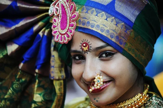 An Indian resident wearing traditional jewellery takes part in a procession celebrating “Gudi Padwa” or the Maharashtrian new year in Mumbai on March 31, 2014. Gudi Padwa is the Hindu new year in the Indian state of Maharashtra and falls on the first day of the month of Chaitra according to the lunar calendar. It is celebrated by dancing and singing with every member of the family wearing new clothes in traditional attire. The day traditionally starts with the cleaning ritual, in which the house is fully cleaned (in case of villages, it is then covered with fresh cow-dung). (Photo by Indranil Mukherjee/AFP Photo)