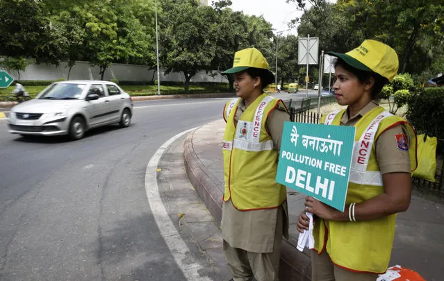 Volunteers remind commuters the reason for restriction placed on vehicle movement in New Delhi, India, Friday, April 15, 2016. The New Delhi government has begun a second round of a two-week car restriction whereby private cars will be allowed on the streets on alternate days from Friday until April 30 based on even or odd license plate numbers, to reduce air pollution that has made the Indian capital the world's most polluted city. (Photo by Saurabh Das/AP Photo)