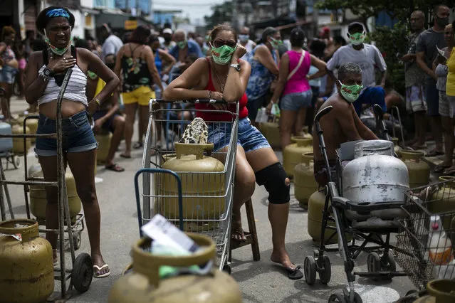 People wearing masks amid the COVID-19 pandemic wait to buy low-cost cooking gas from the Petrobrás Oil Tankers Union in the Vila Vintem favela of Rio de Janeiro, Brazil, Friday, March 12, 2021. The union promoted the sale as part of a solidarity campaign to mark The National Day of Struggles in Defense of State-owned Companies. (Photo by Bruna Prado/AP Photo)