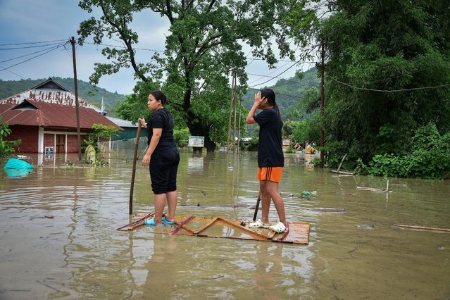 Girls row a makeshift raft to reach a safer place after heavy rains caused by Cyclone Remal in Imphal, Manipur, India on May 29, 2024. (Photo by Reuters/Stringer)