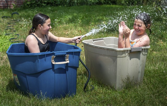 Best friends Anna Labelle, left and Frankie Russell got creative Tuesday morning, June 18, 2024, to help stay cool in Labelle's backyard in Auburn, Maine, as the temperature began to climb. (Photo by Russ Dillingham/Sun Journal via AP Photo)