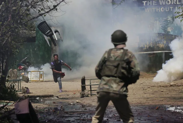 A Kashmiri student throws a chair on Indian policemen as they clash in Srinagar, Indian controlled Kashmir, Monday, April 17, 2017. The clashes on Monday began in Srinagar when hundreds of college students took to the streets to protest a police raid in a college in southern Pulwama town over the weekend, in which at least 50 students were injured. (Photo by Mukhtar Khan/AP Photo)