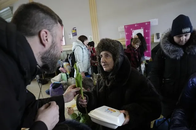 A Catholic priest hands out tulips, to women who have fled Ukraine, in recognition of International Women's Day at the train station in Przemysl, Poland, Tuesday, March 8, 2022. U.N. officials said Tuesday that the Russian onslaught has forced 2 million people to flee Ukraine. It has trapped others inside besieged cities that are running low on food, water and medicine amid the biggest ground war in Europe since World War II. (Photo by Czarek Sokolowski/AP Photo)