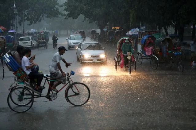 Vehicles are seen on a street during heavy rain in Dhaka, Bangladesh, July 13, 2019. Floods have forced more than four million people from their homes across India, Nepal and Bangladesh and killed more than 100 people as torrential rains in the initial days of monsoons wreaked havoc. (Photo by Mohammad Ponir Hossain/Reuters)