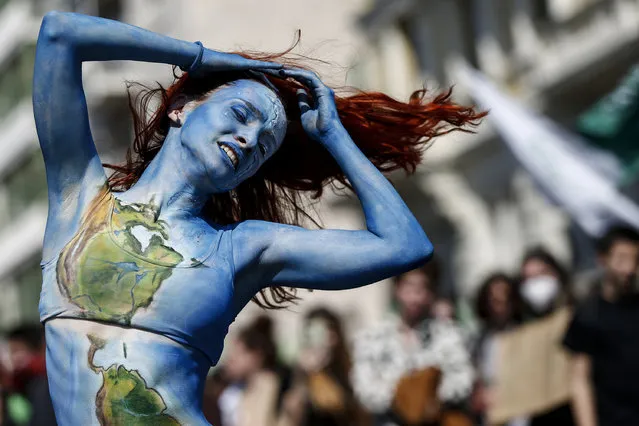 A woman performs a dance during a demonstration for climate justice and against the war in Rome, Friday, March 25, 2022. Climate activists have staged a 10th series of worldwide protests to demand that leaders take stronger action against global warming. (Photo by Cecilia Fabiano/LaPresse via AP Photo)