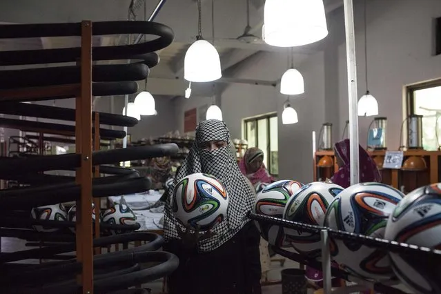 An employee checks the shape of a ball inside the soccer ball factory that produces official match balls for the 2014 World Cup in Brazil, in Sialkot, Punjab province May 16, 2014. (Photo by Sara Farid/Reuters)