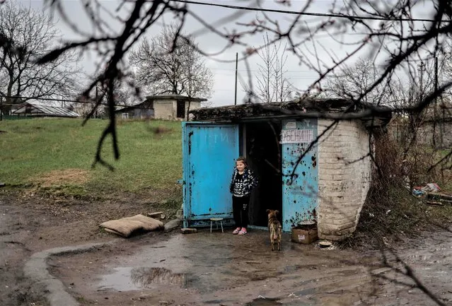 A girl stands by the door of a bunker in Severodonetsk, in eastern Ukraine's Donbass region, on April 13, 2022 as Russian troops intensified a campaign to take the strategic port city of Mariupol, part of an anticipated massive onslaught across eastern Ukraine. (Photo by Ronaldo Schemidt/AFP Photo)