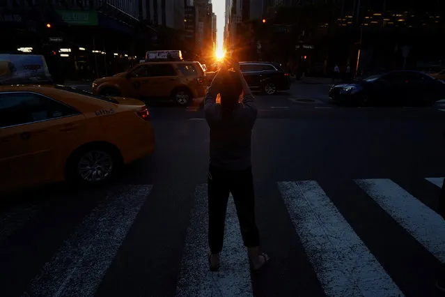 A woman takes a photo as the sun sets while lined up with 42nd Ave a few days after the Manhattanhenge phenomenon in the Manhattan borough of New York City, New York, U.S. May 31, 2017. (Photo by Carlo Allegri/Reuters)