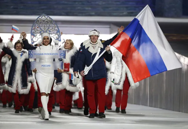 In this February 7, 2014 file photo Alexander Zubkov of Russia carries the national flag as he leads the team during the opening ceremony of the 2014 Winter Olympics in Sochi, Russia. at left is model Irina Shayk carrying the Russian placard. The World Anti-Doping Agency banned Russia on Monday Dec. 9, 2019 from the Olympics and other major sporting events for four years, though many athletes will likely be allowed to compete as neutral athletes. (Photo by Mark Humphrey/AP Photo/File)