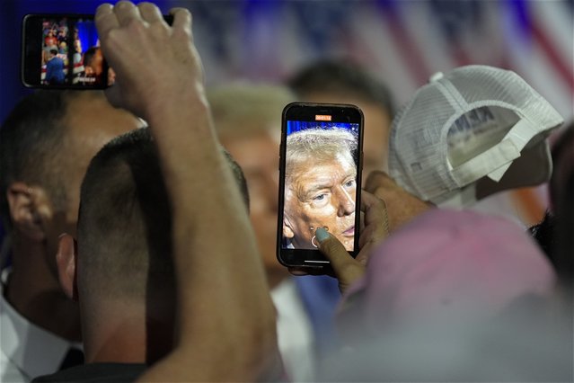 A woman takes a photo of former President Donald Trump as he greets supporters while on the campaign trail at a town hall in La Crosse, Wis., August 29, 2024. (Photo by Morry Gash/AP Photo)