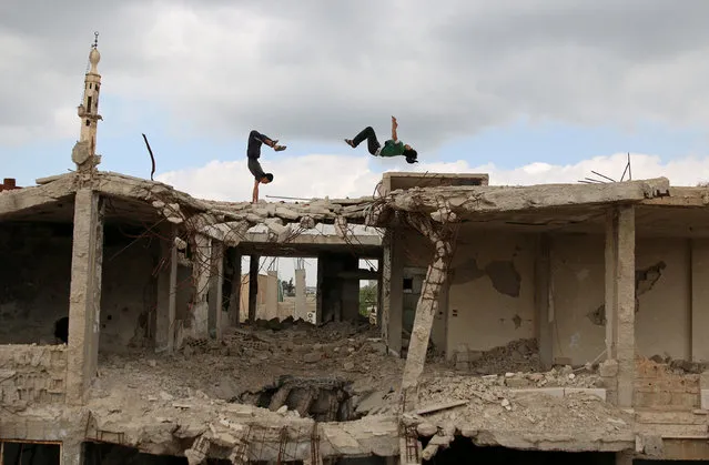 Parkour coach Ibrahim al-Kadiri (R), 19, and Muhannad al-Kadiri, 18, demonstrate their Parkour skills amid damaged buildings in the rebel-held city of Inkhil, west of Deraa, Syria, April 7, 2017. Ibrahim discovered Parkour in Jordan, where he had fled to escape the war. Back in his home town since 2015, he now leads a group of 15 practitioners. (Photo by Alaa Al-Faqir/Reuters)
