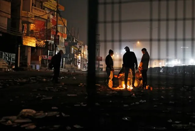 Local residents stand next to a bonfire as they block a road during a protest against a new citizenship law, in New Delhi, India, December 19, 2019. (Photo by Adnan Abidi/Reuters)