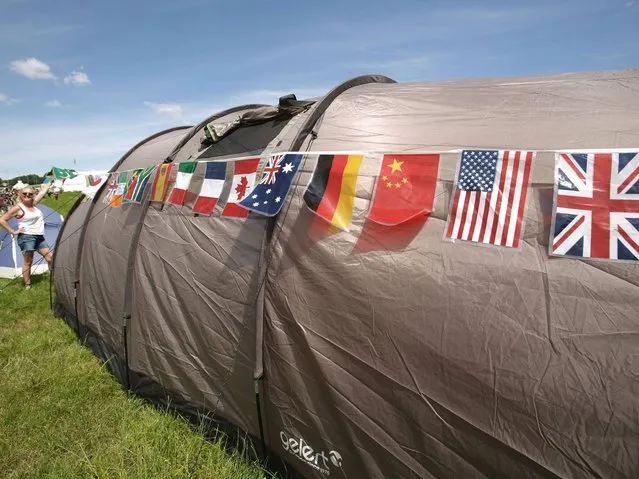 A woman adorns her tent with flags from different nations to celebrate the World Cup, at the Glastonbury Festival, at Worthy Farm in Somerset. (Photo by Yui Mok/PA Wire)
