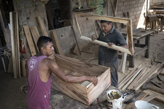 Sergio Morales, right, and Joelvis Cantillo, build a simple coffin at their furniture workshop in Maracaibo, Venezuela, November 20, 2019. Two years ago the carpenters started building coffins for less than $100 instead of furniture due to the high demand for cheaper coffins. (Photo by Rodrigo Abd/AP Photo)