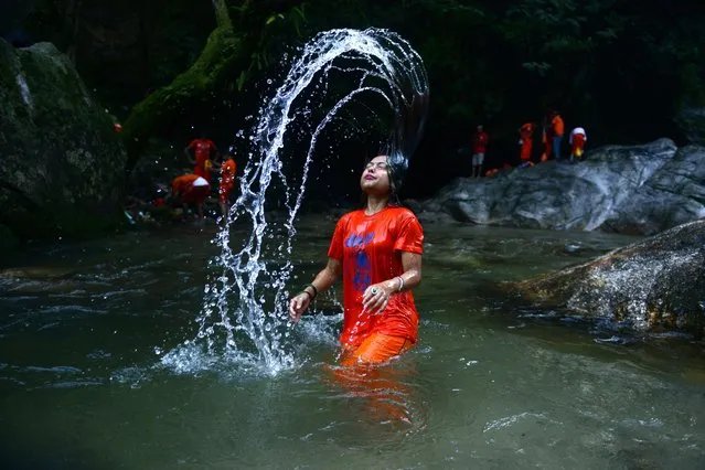 A Nepalese Hindu devotee bathes in the Bagmati River on her way to the Pashupatinath Temple to offer prayers to Lord Shiva, Hindu god of destruction during Shravan festivities in Sundarijal, on the outskirts of Kathmandu on August 3, 2015. According to the Nepali calendar, Shravan is considered the holiest month of the year with each Monday of the month known as Shravan Somvar when worshippers offer prayers for a happy and prosperous life. (Photo by Prakash Mathema/AFP Photo)