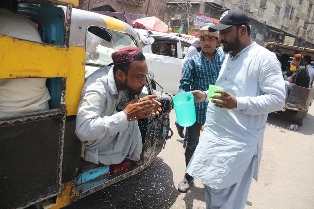 People drink free juice on the roadside, to beat the heat in Hyderabad, Pakistan, 11 May 2022. The Pakistan Meteorological Department (PMD) said that a severe heatwave that has been affecting central and upper Sindh will affect the entire province – including Karachi – for nearly a week starting 11 May, with maximum temperatures expected to exceed 40 degrees Celsius in the provincial capital. (Photo by Nadeem Khawar/EPA/EFE)