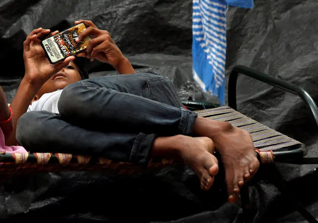 A boy watches a movie on his mobile phone as he lies in a cot on a pavement in Kolkata, India July 5, 2017. (Photo by Rupak De Chowdhuri/Reuters)