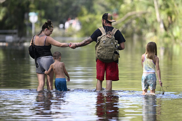 Dustin Holmes, second from right, holds hands with his girlfriend, Hailey Morgan, while returning to their flooded home with her children Aria Skye Hall, 7, right, and Kyle Ross, 4, in the aftermath of Hurricane Helene, Friday, September 27, 2024, in Crystal River, Fla. (Photo by Phelan M. Ebenhack/AP Photo)