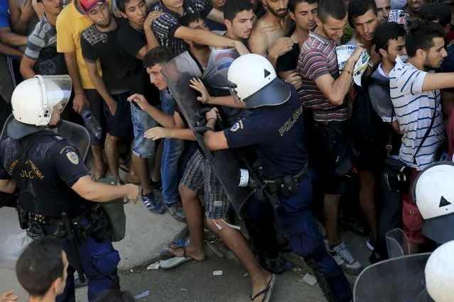 A riot police officer pushes a migrant as he tries to maintain an orderly line during a registration procedure at the national stadium of the Greek island of Kos August 12, 2015. (Photo by Alkis Konstantinidis/Reuters)