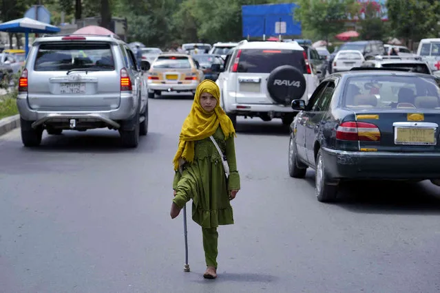 A disabled girl begs in Kabul, Afghanistan, Sunday, May 22, 2022. Some 1.1 million Afghan children under the age of five will face malnutrition by the end of the year. , as hospitals wards are already packed with sick children. (Photo by Ebrahim Noroozi/AP Photo)