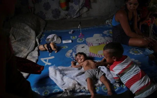 Gregoria Hernandez, 23, sits next to her seven-moth-old daughter Sonia, who according to her has diarrhoea and is underweight, while resting on a bed in Barquisimeto, Venezuela, August 16, 2019. “I feel like the worst of mothers, because I don't have a way to help them, to give them what they need, the food they need”, said Hernandez. (Photo by Carlos Garcia Rawlins/Reuters)