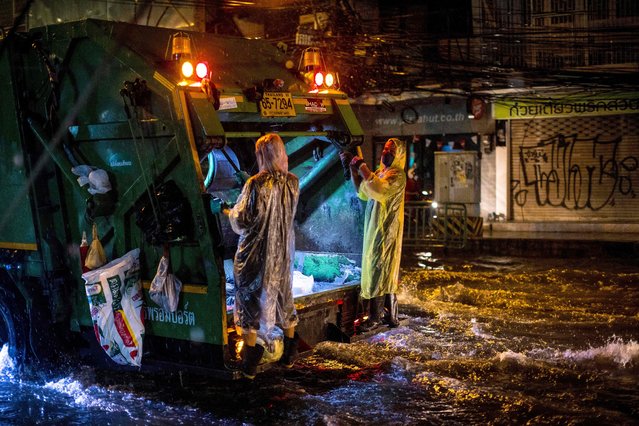 Waste disposal workers wear ponchos as they ride down a flooded street after heavy rain in Bangkok on May 18, 2022. (Photo by Jack Taylor/AFP Photo)