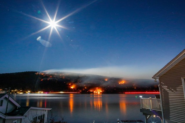 Smoke rises from the Jennings Creek Wildfire as the moon rises over Greenwood Lake on November 13, 2024 in Greenwood Lake, New York. An extended drought has helped fuel the Jennings Creek Wildfire on the New York/New Jersey border, which has grown to 5,000 acres across both states. (Photo by Kena Betancur/Getty Images)