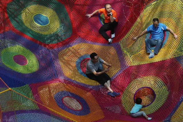 Visitors enjoy a mega hand-knitted crocheted playscape created by Japanese textile artist Toshiko Horiuchi MacAdam at an art exhibition entitled “Harmonic Motion” in Hong Kong, Saturday, July 9, 2016. (Photo by Kin Cheung/AP Photo)