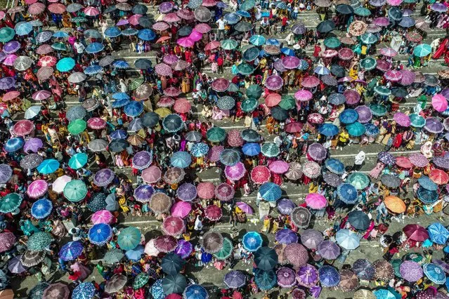 This aerial picture shows spectators carrying umbrellas gathered during the annual Behdienkhlam festival which is celebrated annually after the sowing period in Tuber village in India’s north-eastern state of Meghalaya on July 22, 2022. (Photo by Biju Boro/AFP Photo)