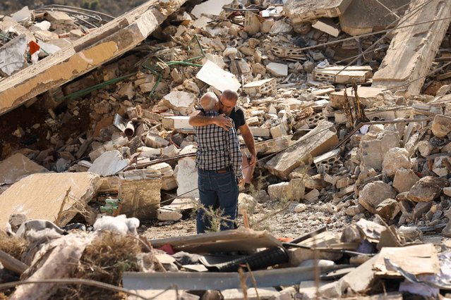 People hug as they stand on rubble of damaged buildings in the aftermath of Israeli strikes, amid the ongoing hostilities between Hezbollah and Israeli forces, in Joun village in the Chouf district, Lebanon on November 13, 2024. (Photo by Aziz Taher/Reuters)