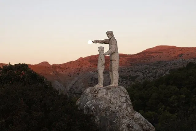 A view of statues of a man and a boy, a monument dedicated to forest rangers, as the supermoon sets over the horizon at dawn at the Sierra de las Nieves (Mountain range of Snows) nature park and biosphere reserve between El Burgo and Ronda, near Malaga, southern Spain August 11, 2014. (Photo by Jon Nazca/Reuters)