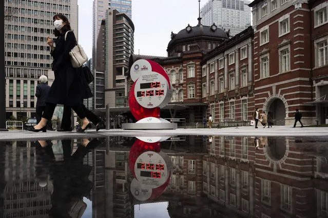 A countdown clock for the Tokyo 2020 Olympics is reflected in a puddle of water outside Tokyo Station in Tokyo, Monday, March 23, 2020. The IOC will take up to four weeks to consider postponing the Tokyo Olympics amid mounting criticism of its handling of the coronavirus crisis that now includes Canada saying it won't send a team to the games this year and the leader of track and field, the biggest sport at the games, also calling for a delay. (Photo by Jae C. Hong/AP Photo)